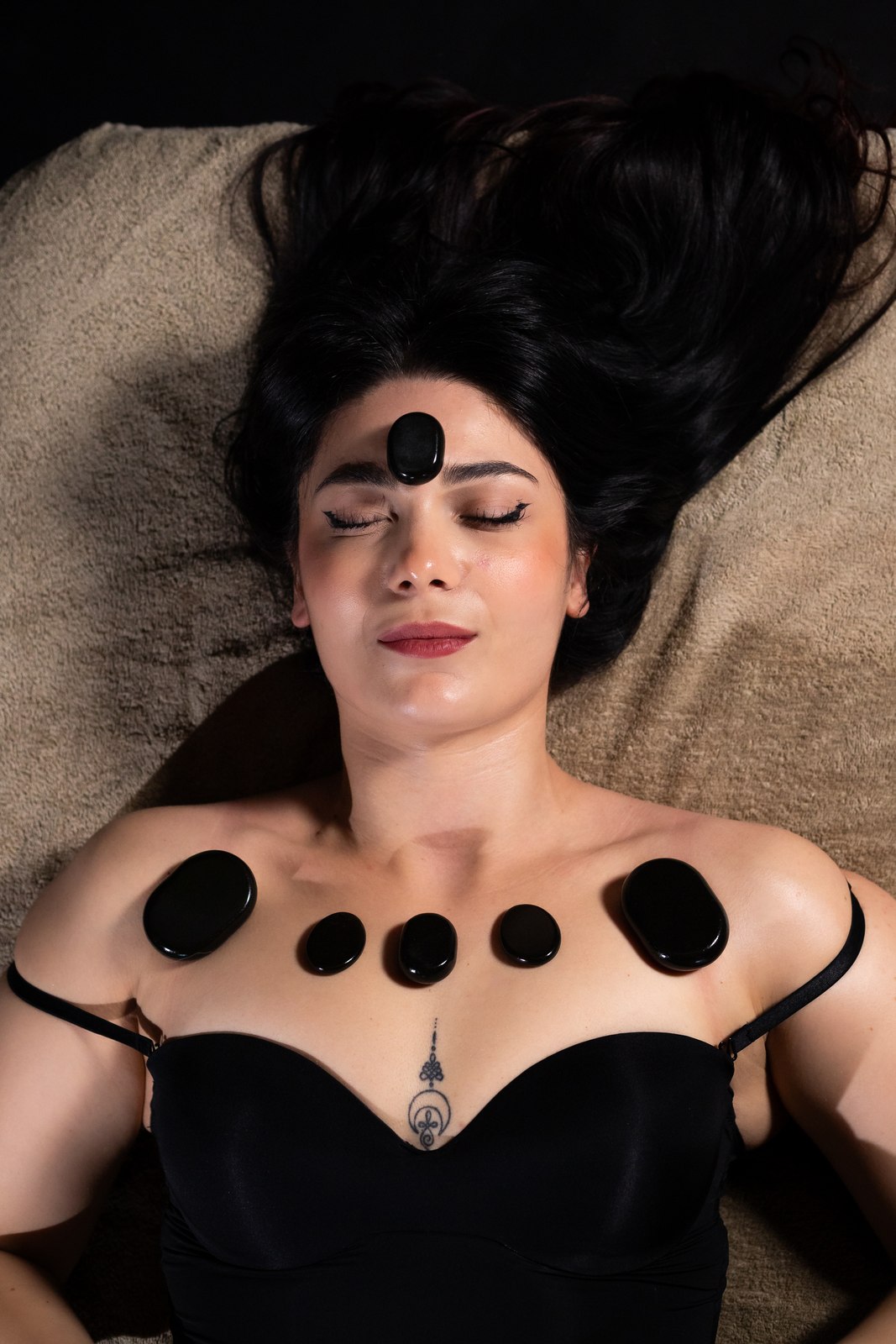 Pietre nere appoggiate su décolleté e fronte durante il rituale Hot Stone